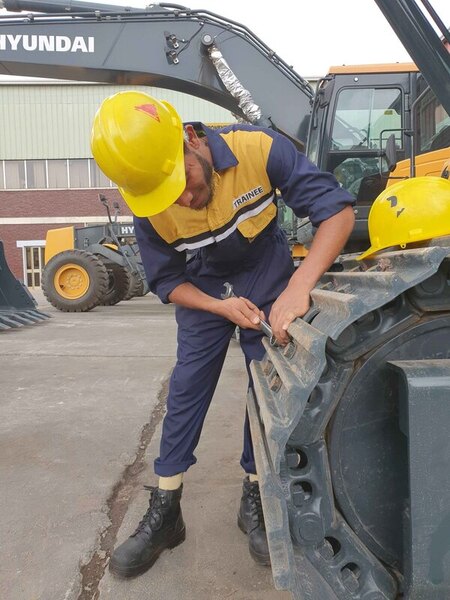 man in yellow hardhat fixes excavator track