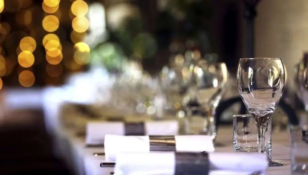 Event table set up with wine glasses and silverware laid out on a long table.