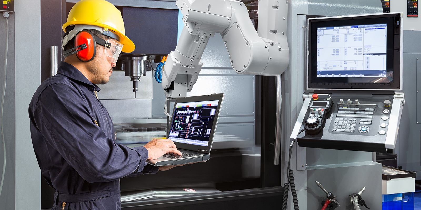 man working alongside robot Maintenance engineer using laptop