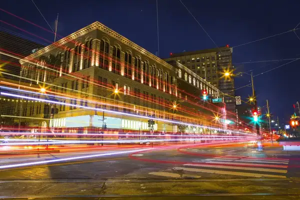 Car lights streaming past a building at night 