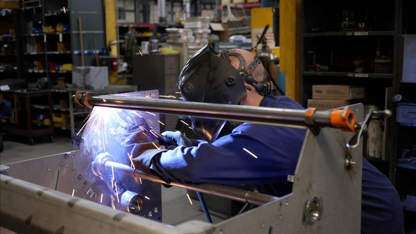 worker in factory using grinder on machine