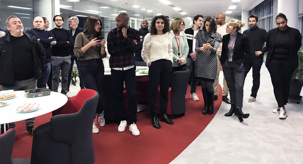 group of people stand near food on table in office