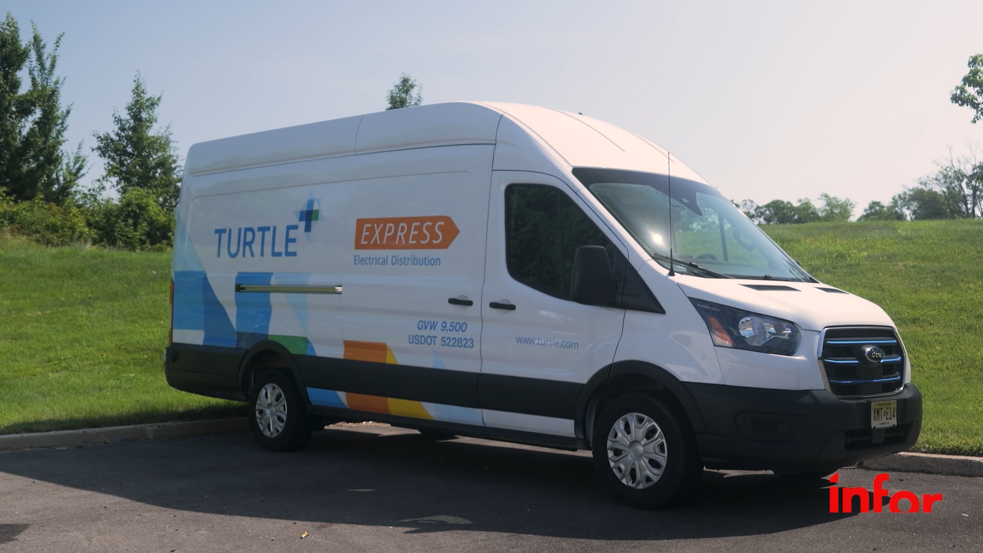 A white Turtle distribution van parked on pavement near grass under a clear sky.
