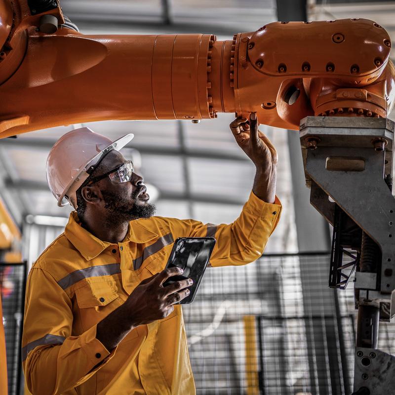 African engineer with tablet inspection the Robotic arm and working at manufacturing process