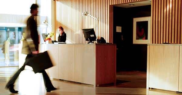 hotel guest in lobby with briefcase walking past front desk