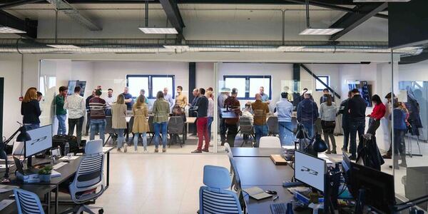 office workers stand in meeting desks computers