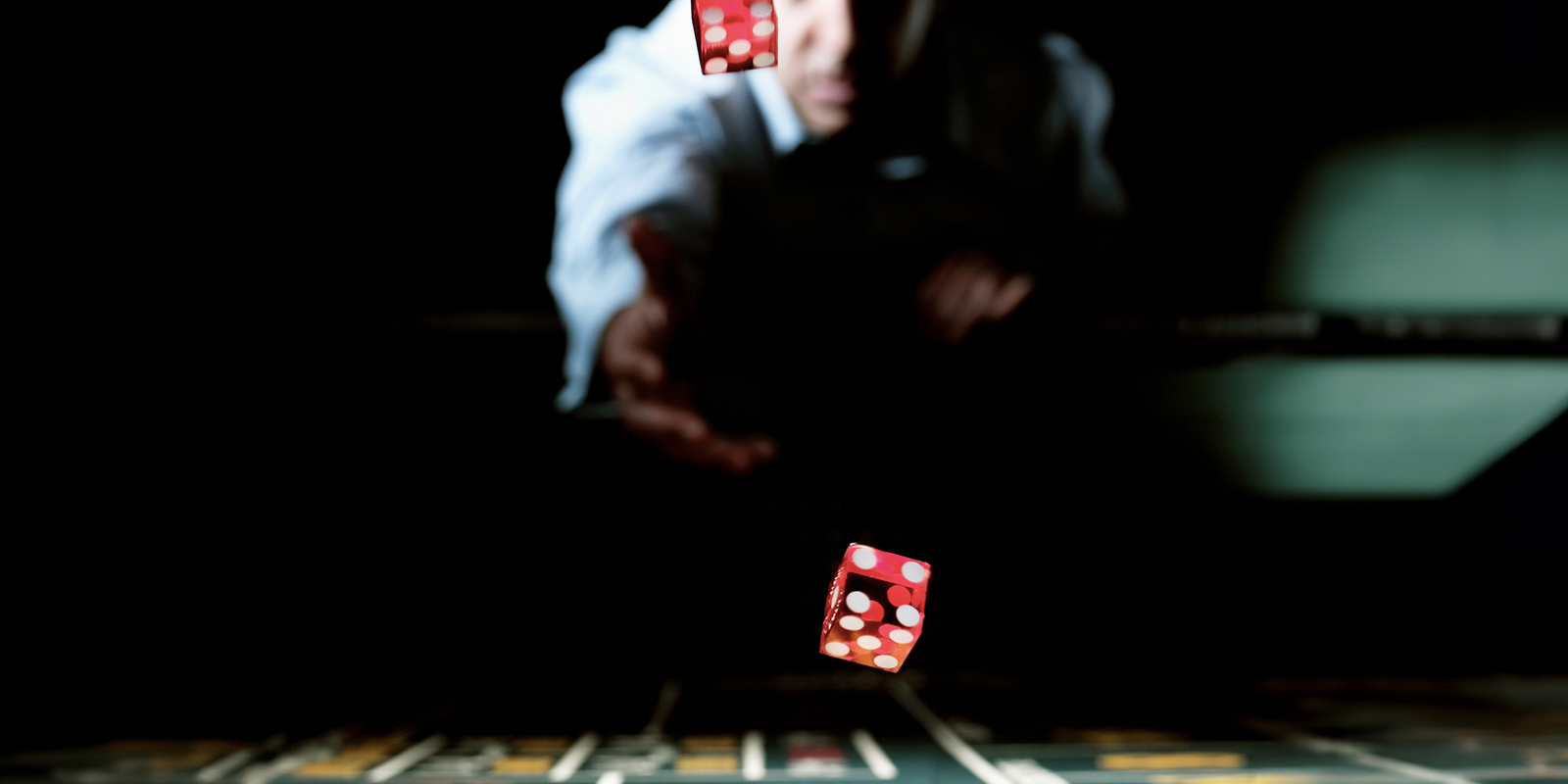 Man throwing dice across gaming table