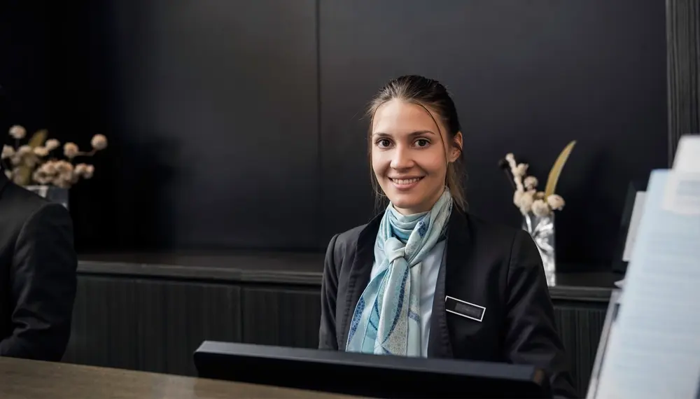 A front desk employee gives a warm and welcoming smile