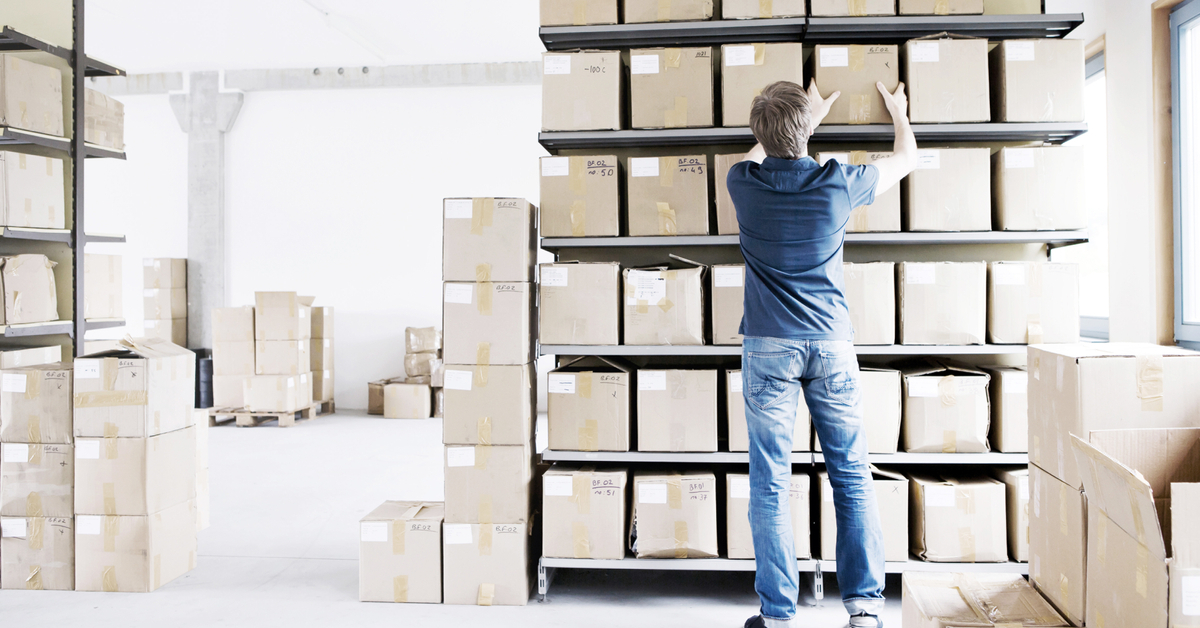 Man filing cardboard boxes in storage