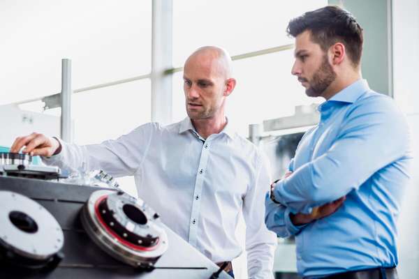 Two business men inspecting a machine inside a brightly lit laboratory