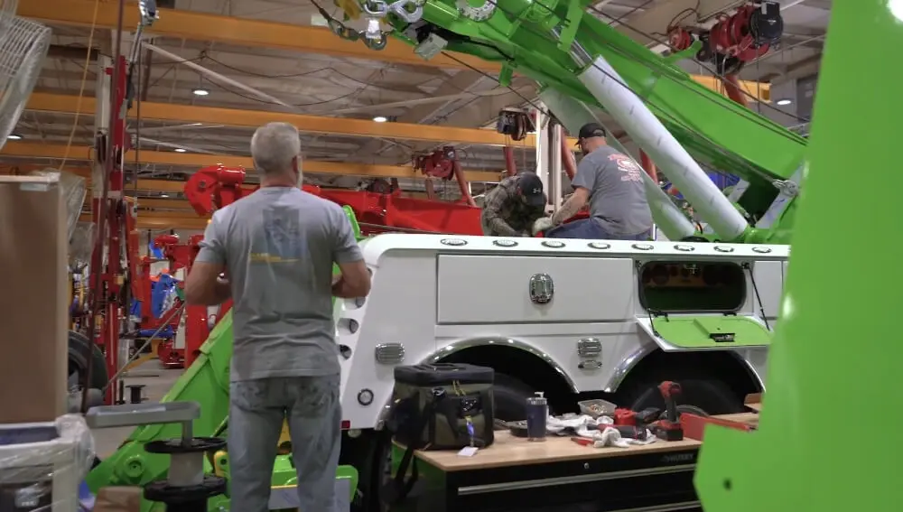Manager supervising the assembly of towing equipment in a factory