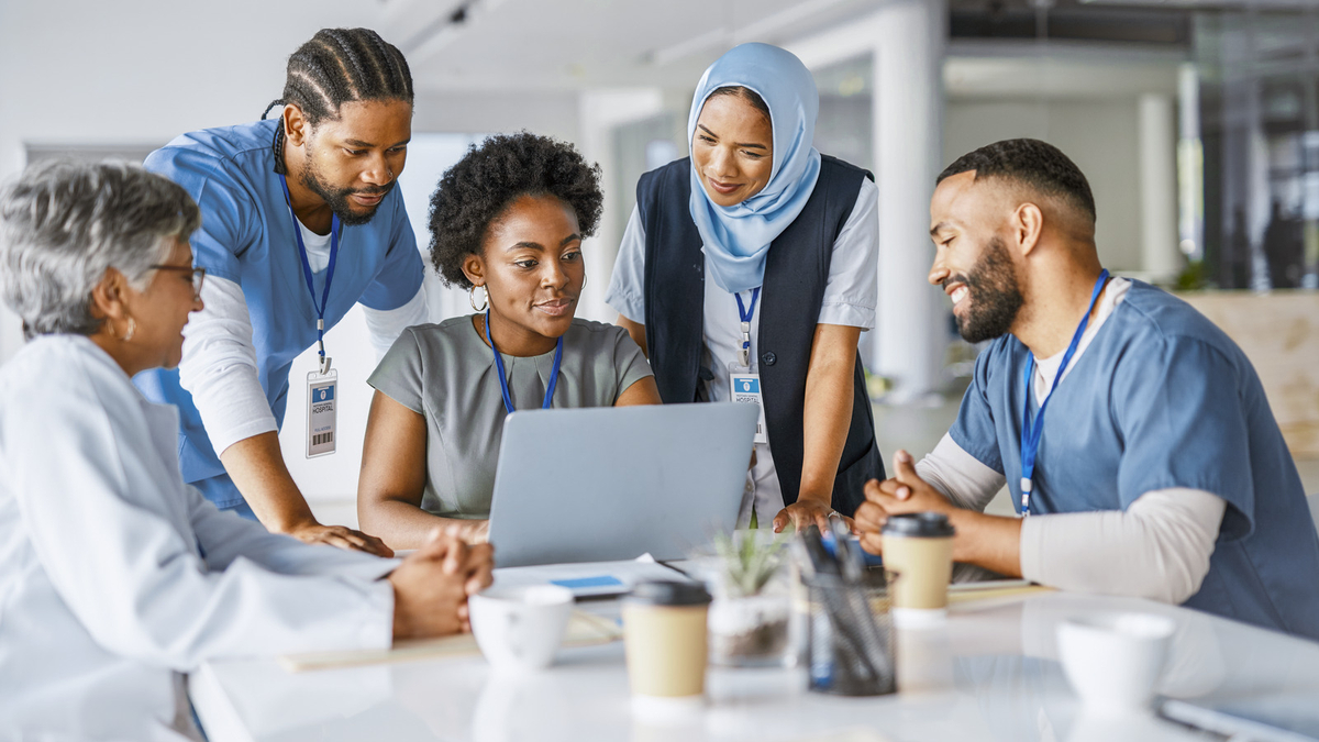 Healthcare team collaborating around a laptop 