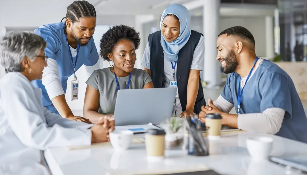 Healthcare team collaborating around a laptop 