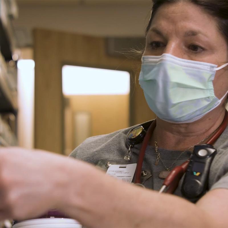 masked woman stocking hospital supply room