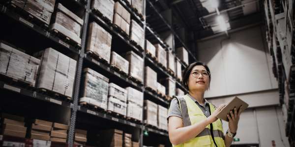 Asian woman using digital tablet working at a warehouse