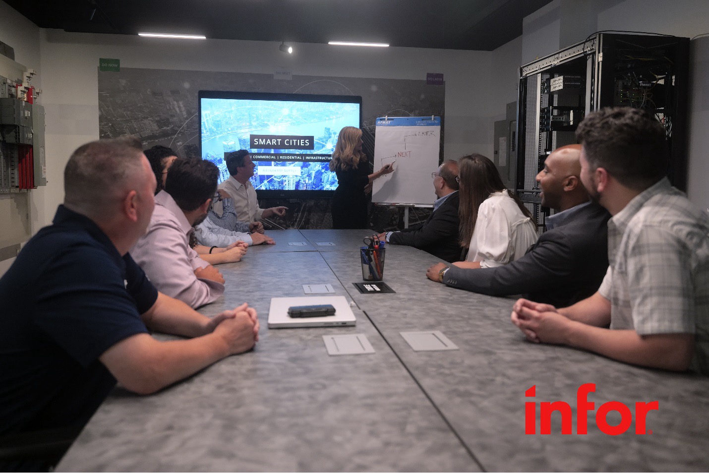 Group of employees in a meeting room with a woman presenting