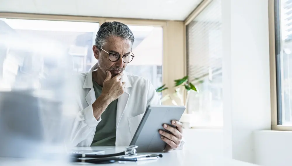 Man in lab coat using tablet PC