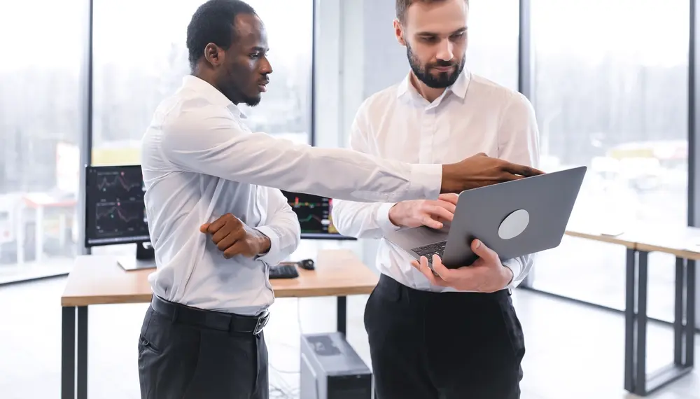 Two colleagues reviewing data on a laptop