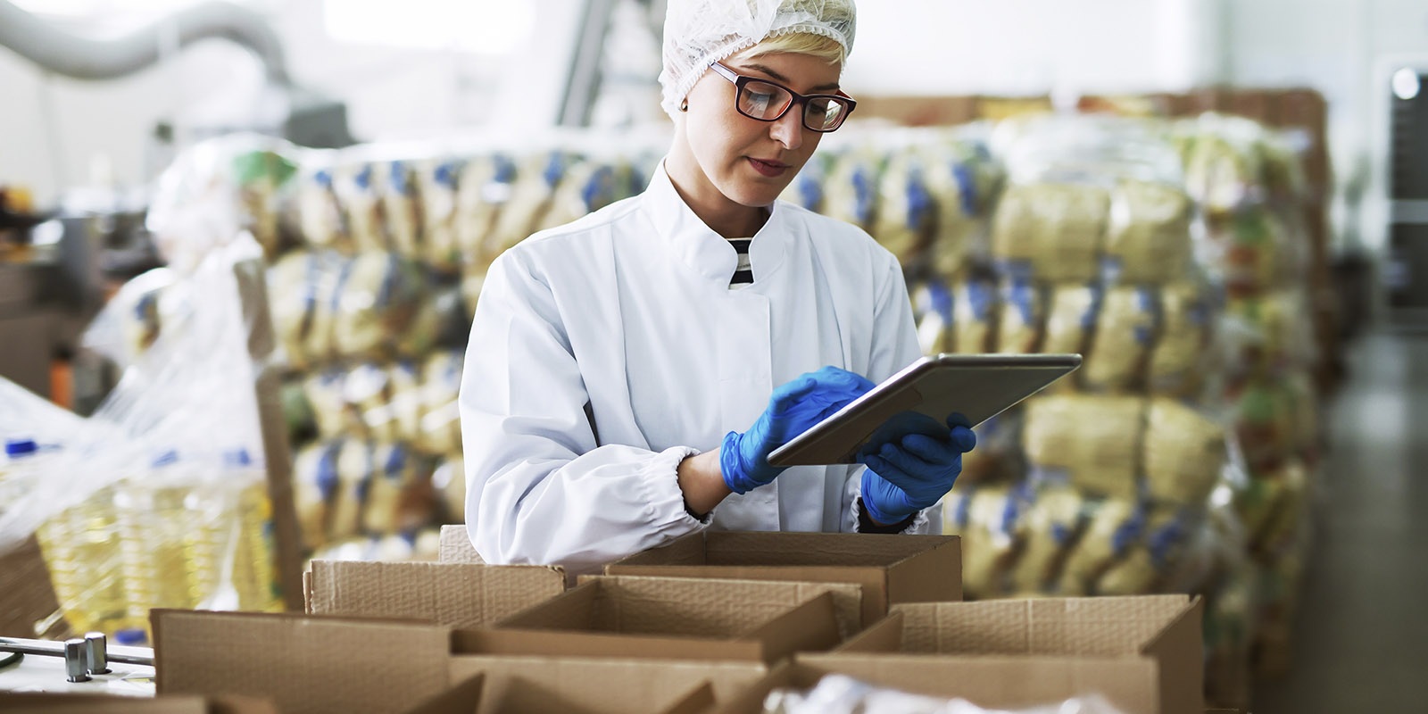 Female worker using tablet checking boxes standing food
  factory   