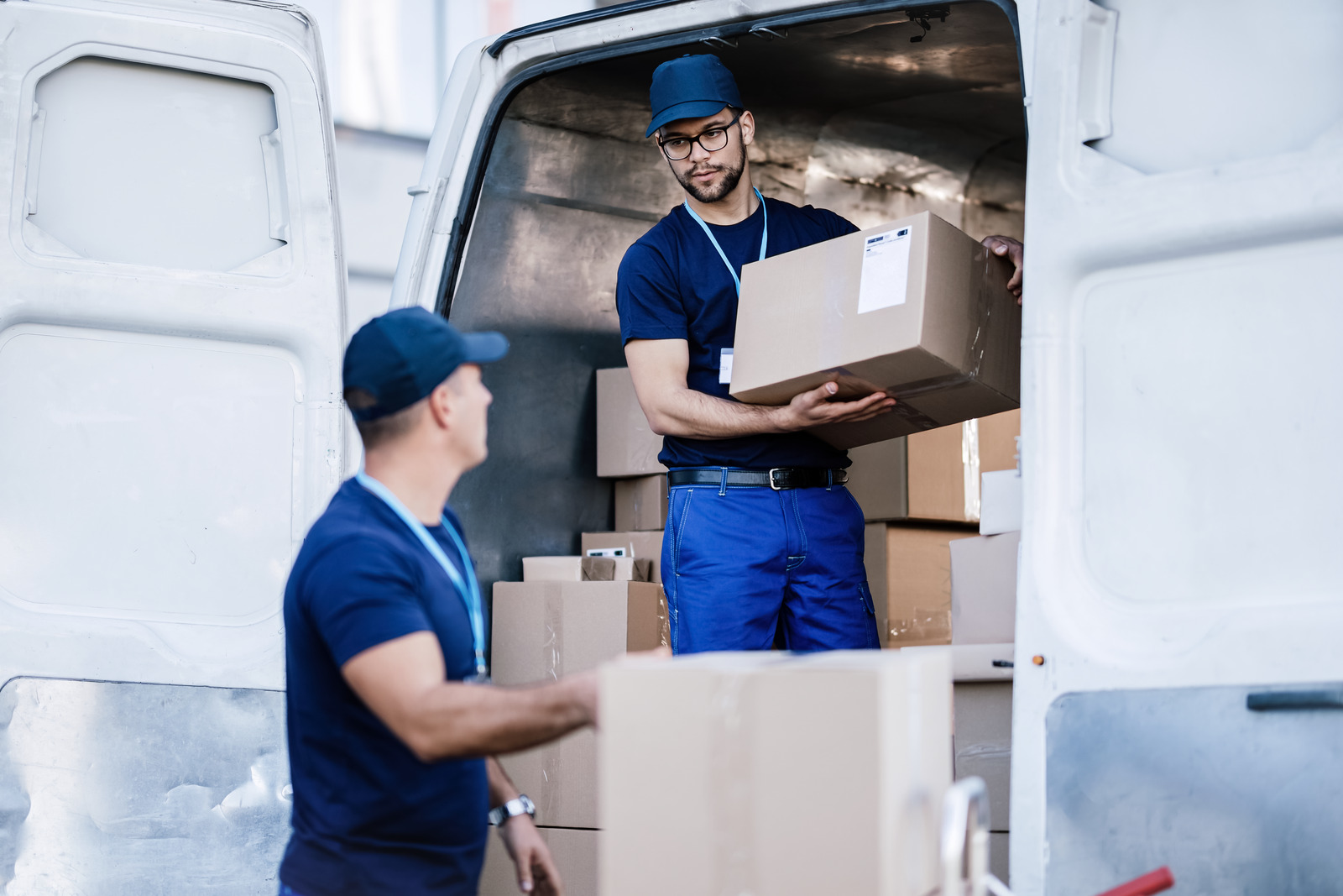 Delivery man talking with coworker while loading boxes. Global Transportation