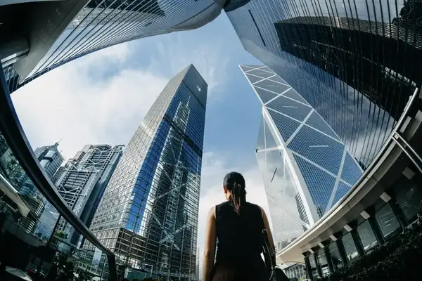 Businesswoman looking up to the sky, surrounded by buildings