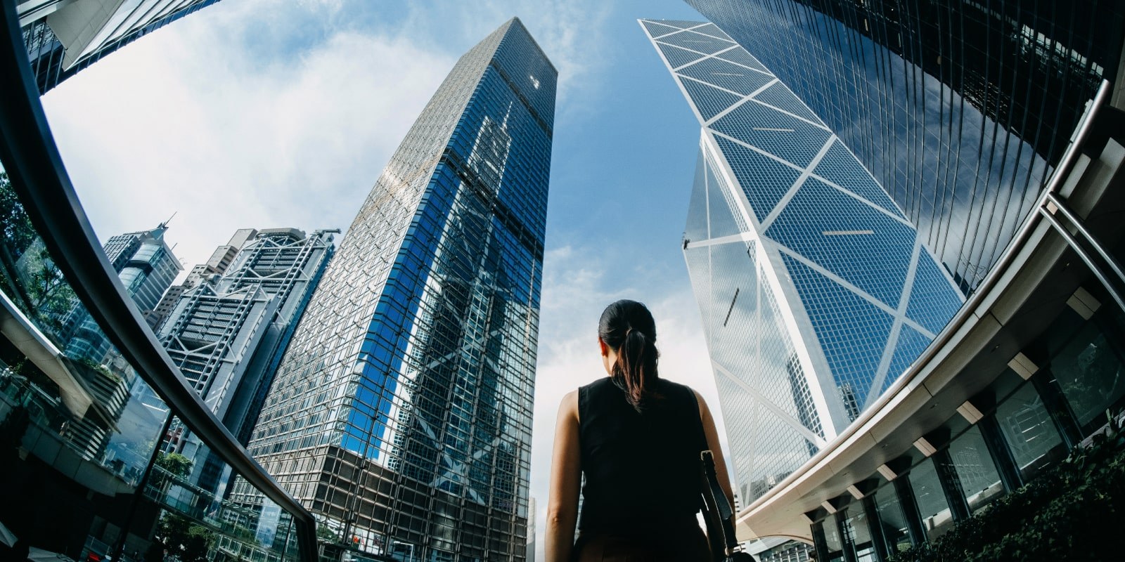 Woman looking up at white clouds in a blue sky 