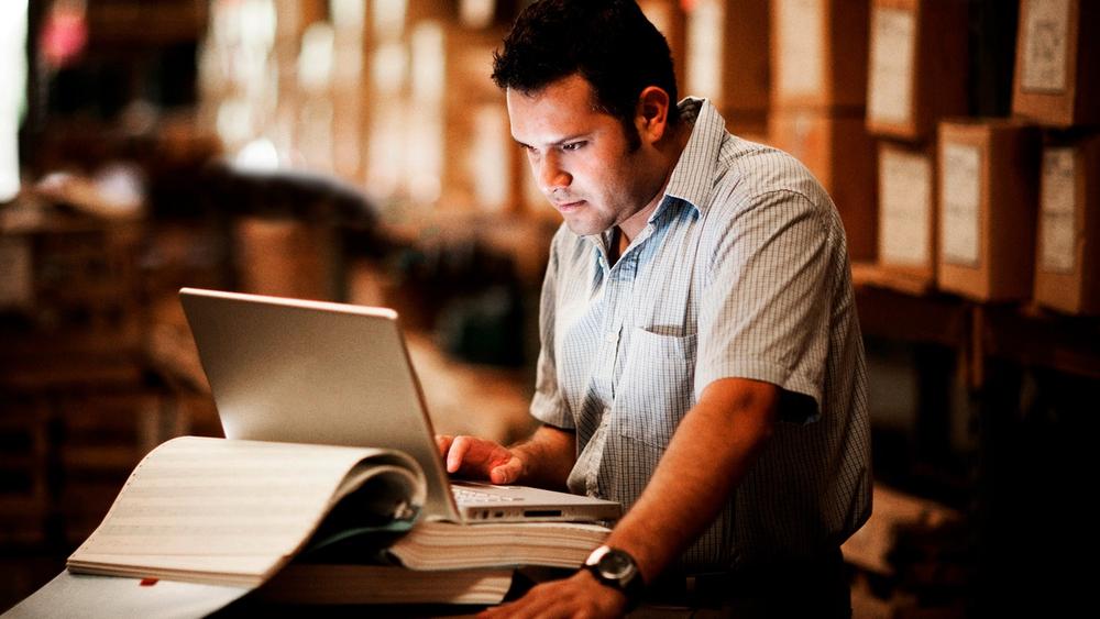 Warehouse worker using supply chain software on a laptop