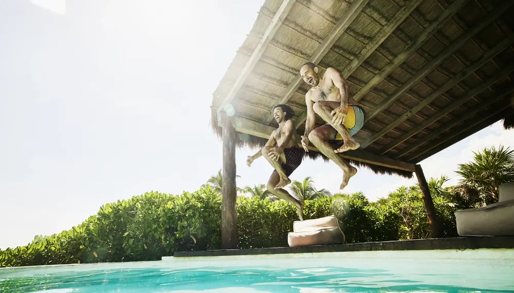 Two men cannonballing into a pool