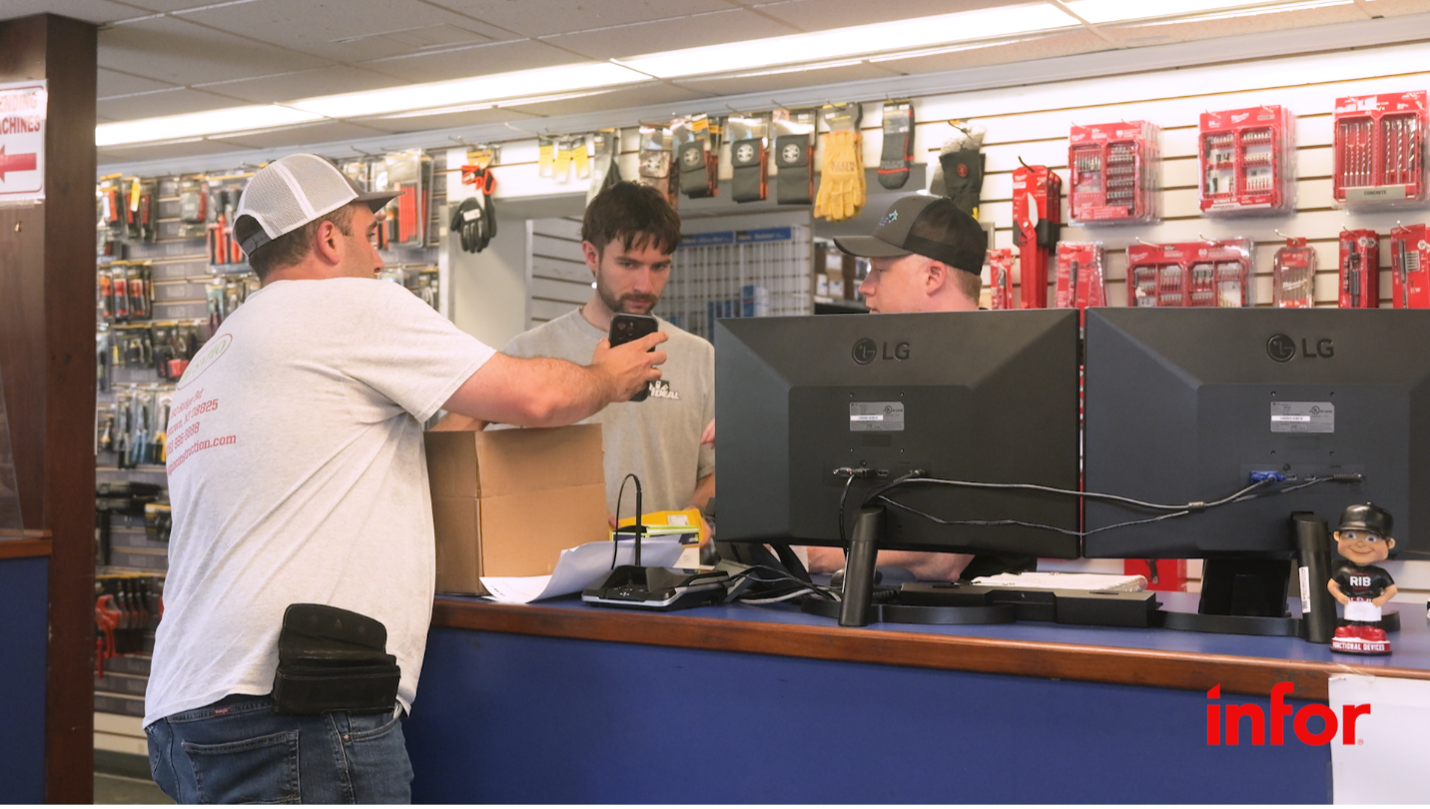 Counter-front image of customer showing phone screen to two employees