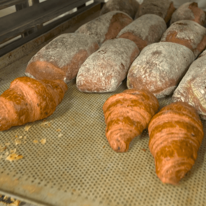 Freshly baked croissants and loaves of bread on a baking tray