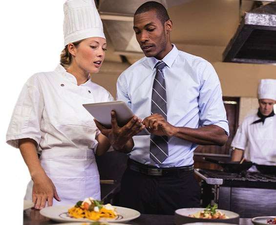A restaurant manager and chef using software for restaurants to review business data on a tablet device