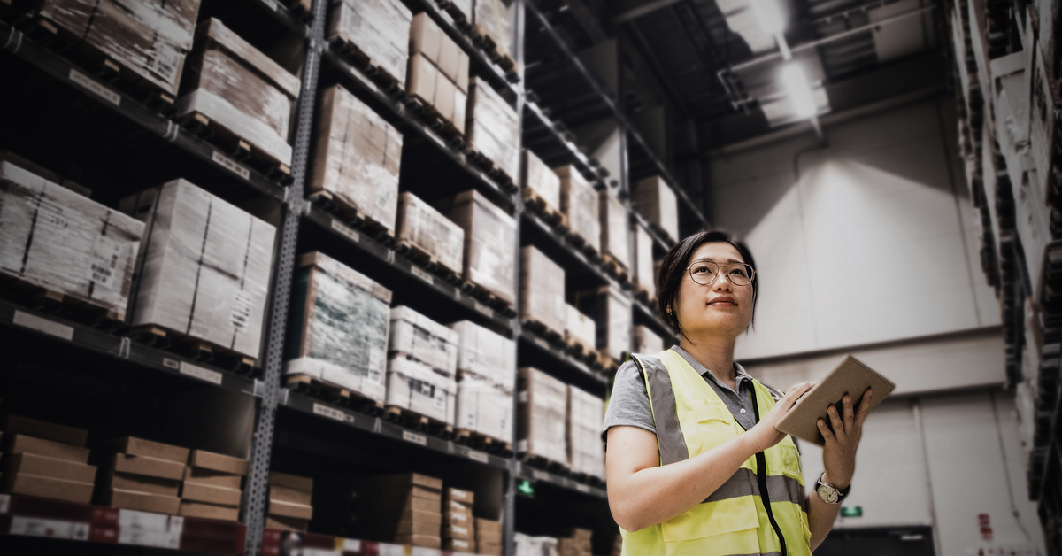 Asian woman using digital tablet working at a warehouse