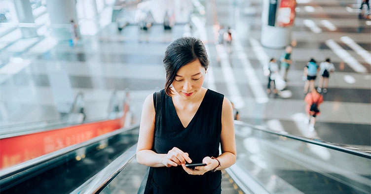 Woman on escalator with mobile phone