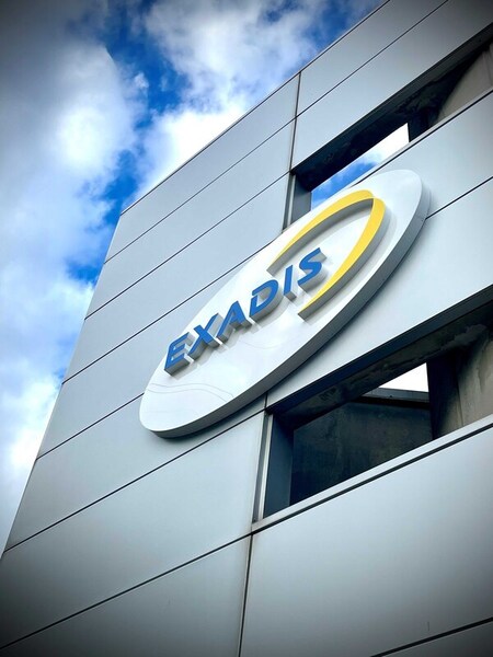 Exadis logo on  gray building facade with sky