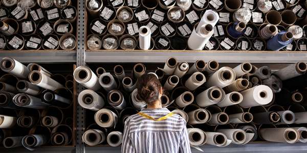 textile designer choosing fabric from stack of rolls