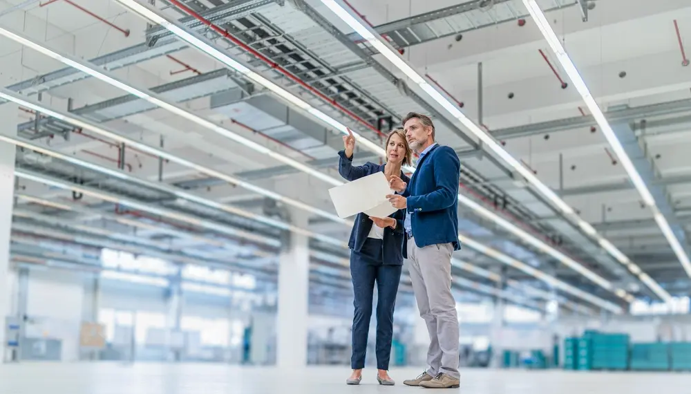 Colleagues in factory hall discussing software automation strategies