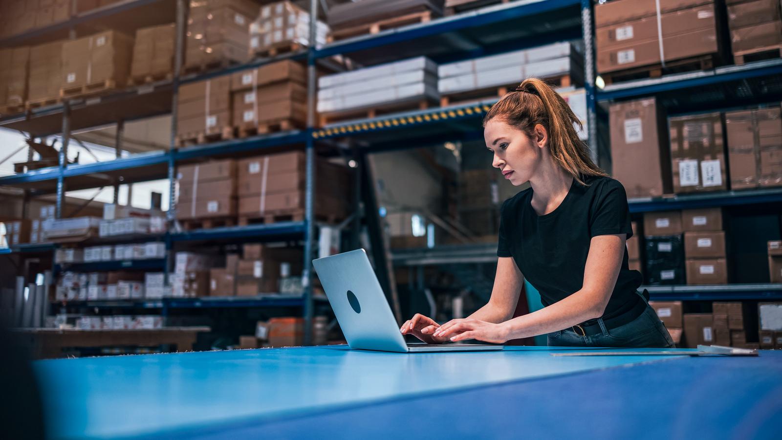 Woman using laptop at warehouse