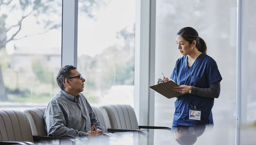 Tablet discussing with male patient in waiting room