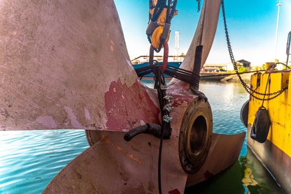 ship propeller hangs from chain in water