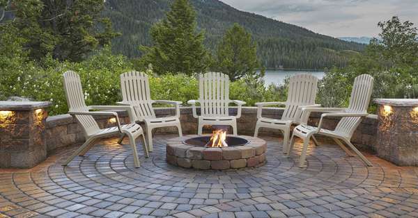 outdoor chairs around patio firepit with lake and mountains