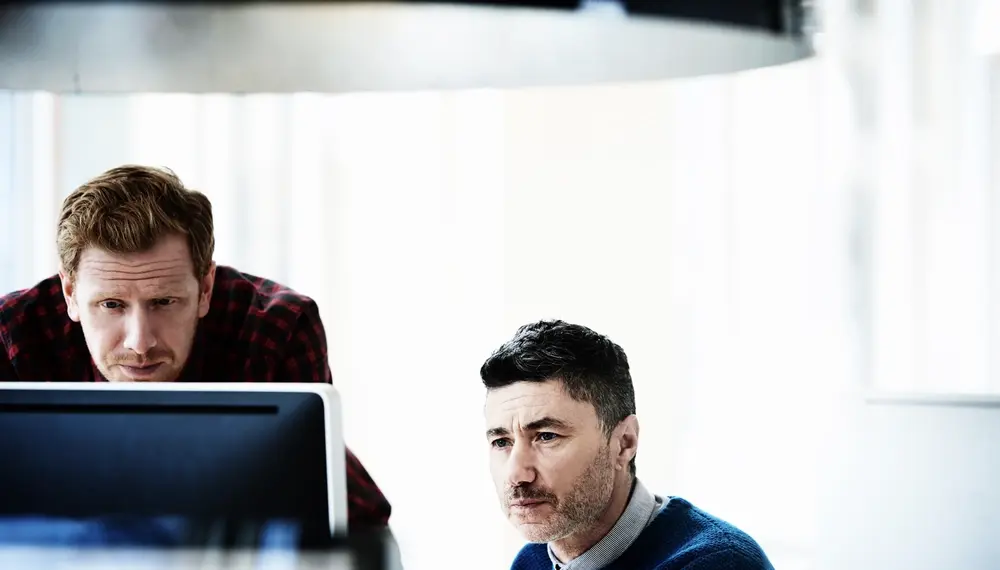 Colleagues reviewing ethics standards on a desktop computer