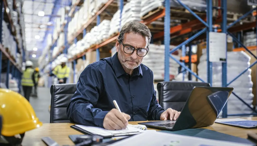 Supply planner reviewing inventory and demand data on monitors in a distribution center