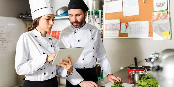 male and woman chefs working on a digital tablet