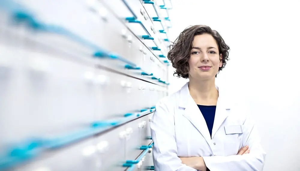 Pharmacist standing beside drawers of medications 