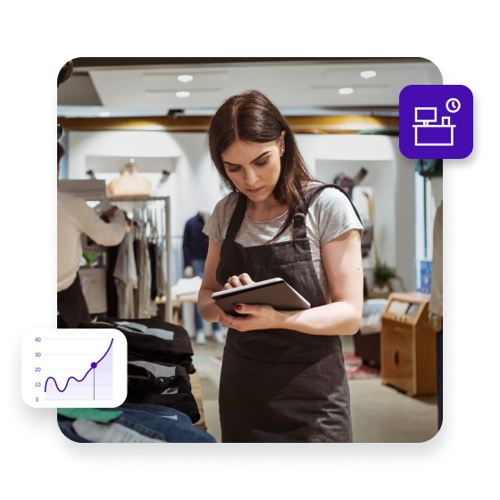 Female owner using digital tablet while coworker arranging clothes on rack at store