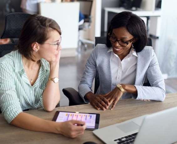 Two women using Infor billing system on a tablet