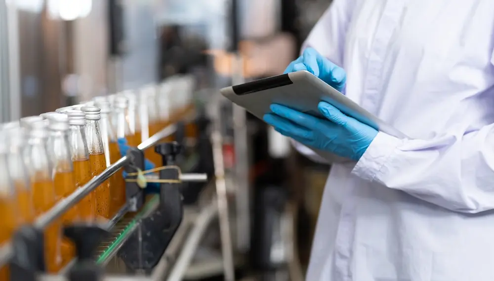 Worker with a tablet at a bottling production line