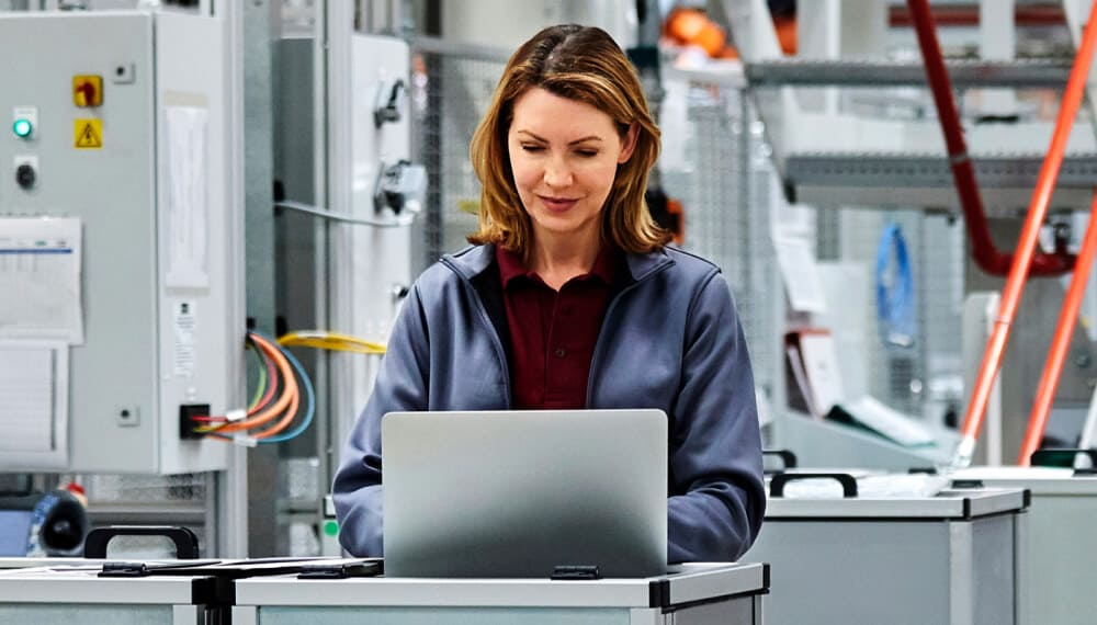 Female manager using Infor MES on her laptop inside a factory for shop floor operations