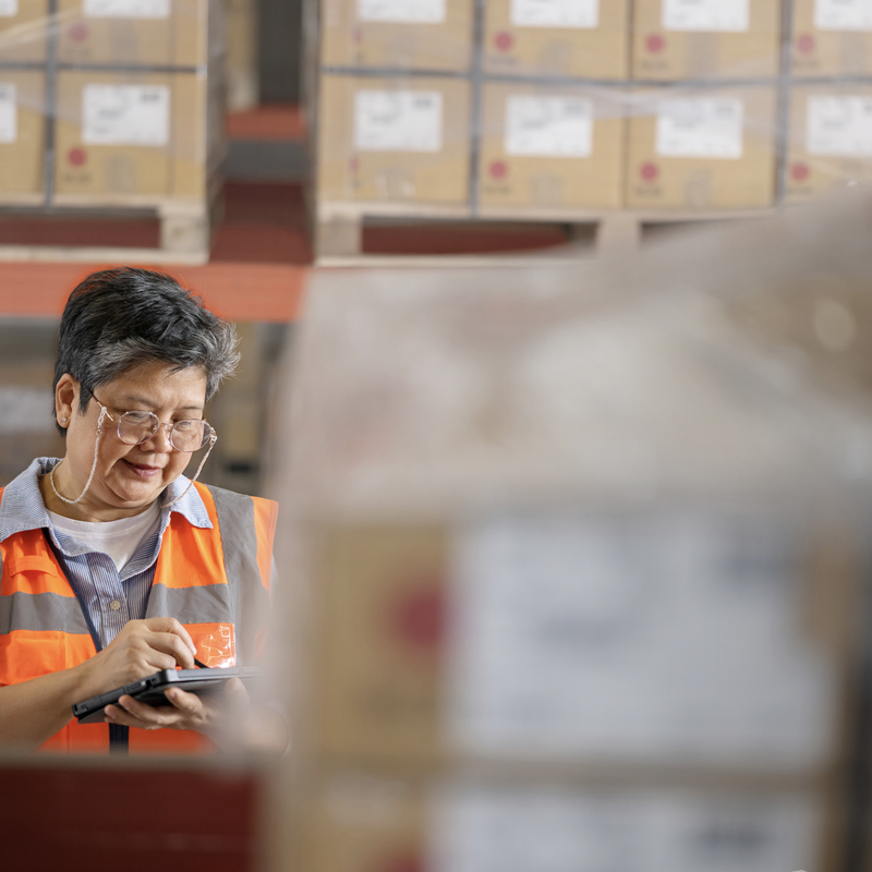 Senior warehouse manager using a digital tablet while working in a distribution warehouse