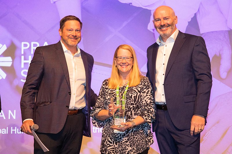 Marna Carlson, PRA Health Sciences director of HR systems, accepts a 2019 Infor Customer Excellence Award from Infor GMs Rod Johnson and Cormac Watters at Inforum